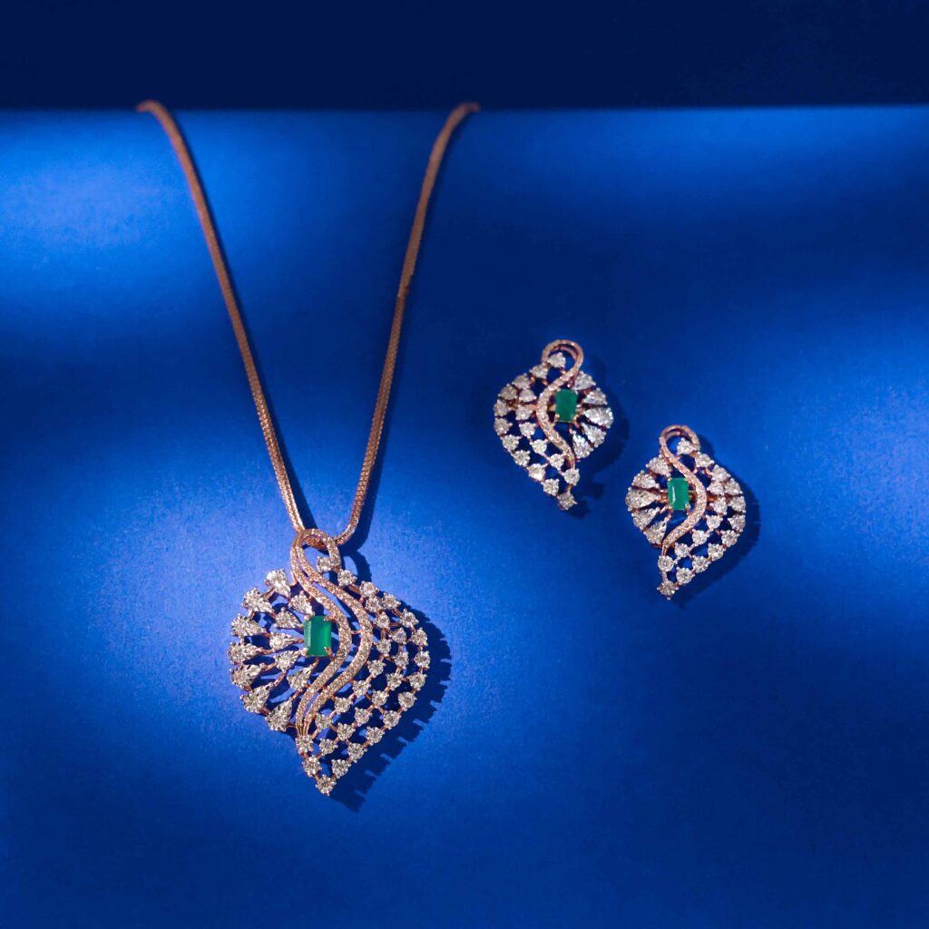 Emerald Glow diamond pendent set with emerald center stone and leaf inspired diamond design in 18k gold with matching earrings