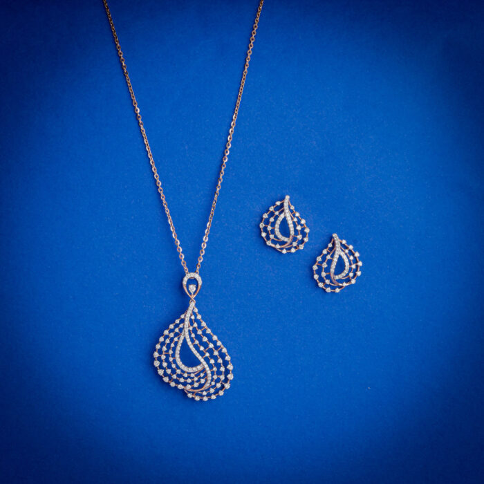 14kt gold diamond pendant set featuring a layered teardrop design with intricate diamond detailing and matching earrings.