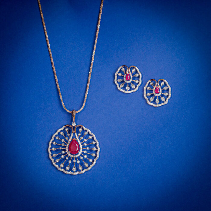 Diamond pendent set with circular openwork design and pear shaped ruby center with matching earrings in 14k gold